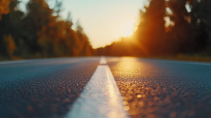 A close-up of an empty asphalt road, focusing on the white dashed lane markings, with a blurred background creating a sense of depth and serenity.