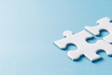 Obraz premium Two white puzzle pieces connected on a light blue background.