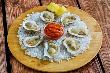 oysters on the half shell served with cocktail sauce on a wooden platter