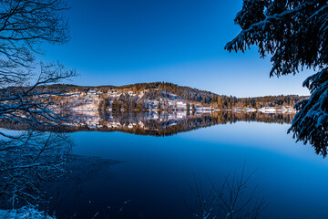 The Winter's Landscape by the Lake with clear reflection on a sunny day in Southern Germany 