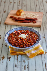 simmered baked beans topped with raw onion served in a blue bowl