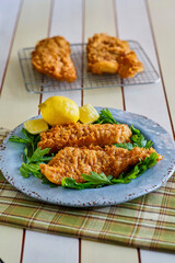 crispy fried fish fillets served on a blue plate with fresh lemon and parsley