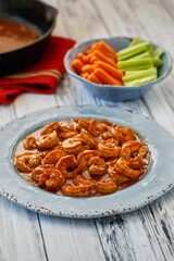 BBQ hot shrimp served on a blue plate with carrots and celery