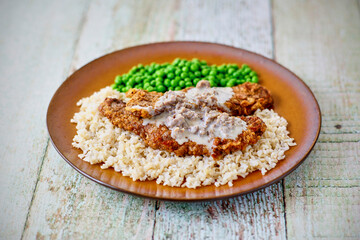 Chicken fried steak with sausage gravy on a brown plate