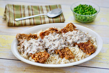 Chicken fried steak with sausage gravy on a white plate