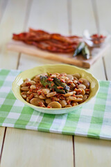 Simmered butter beans with bacon in a yellow bowl