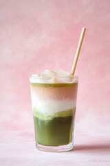 Refreshing layered matcha and strawberry latte served in a glass with eco-friendly straw on a playful pink background