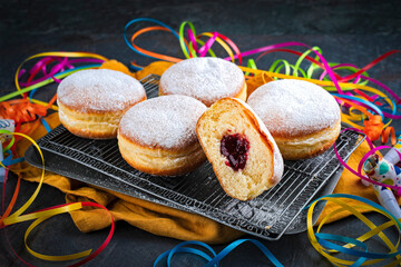 Naklejka premium Authentic traditional German festive Berliner Krapfen - jam doughnut with icing sugar and carnival party decoration