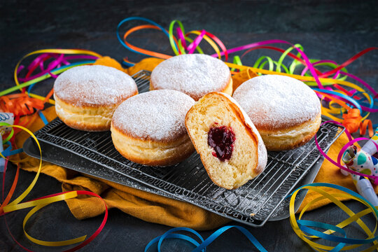 Authentic traditional German festive Berliner Krapfen - jam doughnut with icing sugar and carnival party decoration
