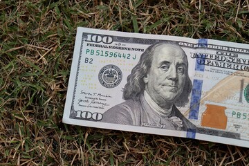 Close up 100 Dollar bank note on grass background. One hundred American dollars.