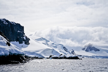 snow covered mountains and rocks in antarctica with ocean © SPARKLINGTRAVEL