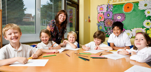 Elementary School: Class Mates. A medium group of primary school children in class with their teacher in a relaxed mood.