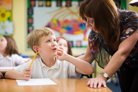 Elementary School: Problem Solved. A moment of understanding from a young primary school pupil beginning to understand his subject with a little help from his teacher in the classroom.