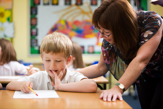 Elementary School: A Maths Problem. A moment of understanding from a young primary school pupil beginning to understand his subject with a little help from his teacher in the classroom.