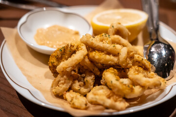 Close-up photo of Fried Squid or Calamari with lemon served on plate.