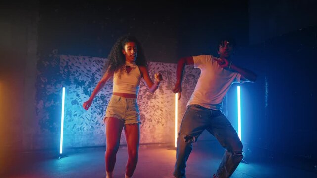 Couple of dancers expressing themselves through contemporary dance steps. African American man and woman moving bodies by rhythm, dancing hip-hop and dancehall, battle in street dance competition