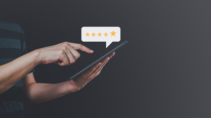 Close up of male customer hand pressing on smartphone screen with golden five star rating feedback icon