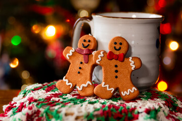 two gingerbread cookies in front of a christmas tree