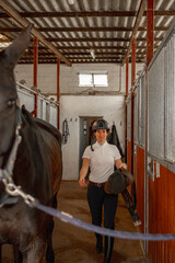 Woman rider preparing the saddle of her horse before riding