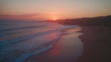 Coastal sunset, waves on sandy beach.