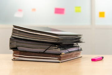 Une pile de dossiers et un surligneur posés sur un bureau