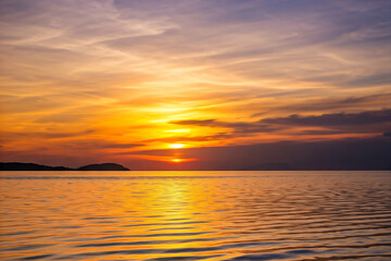 Obraz premium Golden hour sunset illuminating ocean waves crashing on sandy sea beach with colorful cloud sky