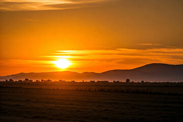 Golden hour sunset illuminating ocean waves crashing on sandy sea beach with colorful cloud sky