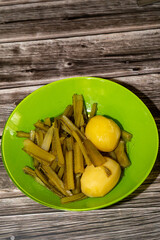 Green borage plate with potato on a wooden table