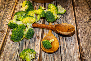Fresh broccoli pieces with stalks and kitchen spoons on table