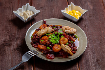 beans stewed with meat and dried fruits and sauce and hummus on a wooden table