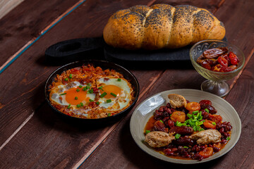 Jewish food shakshuka tzimmes with beans and dried fruits and fresh challah on the table....