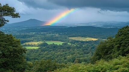 Rainbow over lush green valley and mountains.