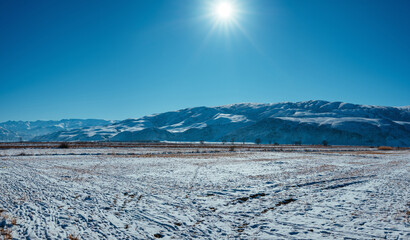 Winter mountains landscape with bright sun in blue sky