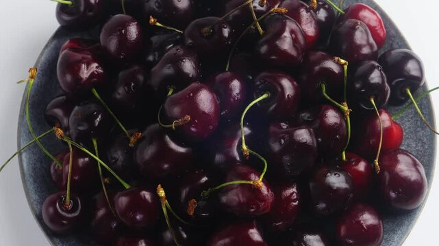 Scattering of ripe dark red cherries rotating in a circle. Medium plan
