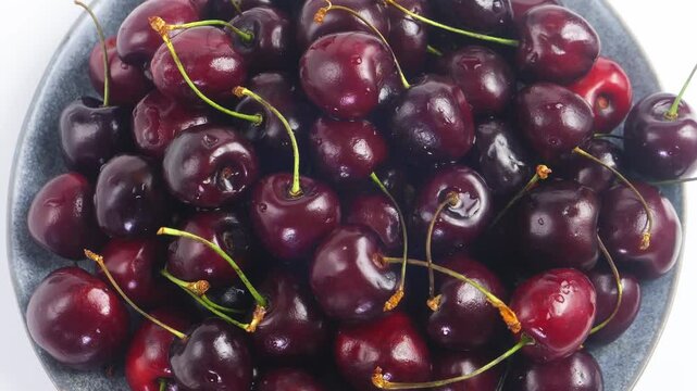 Scattering of ripe dark red cherries with branches rotating in a circle. Medium plan