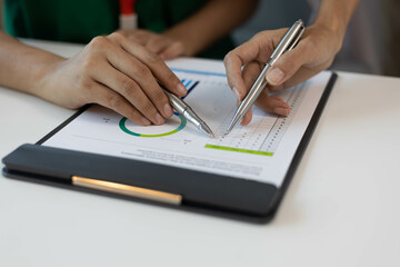 A womam are looking at a clipboard with a list of things to do. They are both holding pens and seem to be discussing the list
