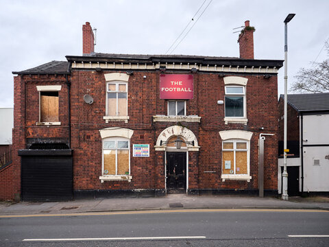 Vacant pub in Swinton 'The Football' with boarded windows on a quiet street.