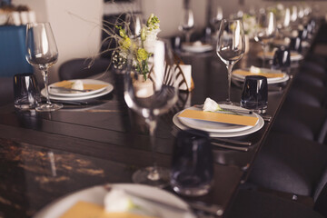 luxury tableware beautiful table setting in restaurant. banquette luxury arrangement plates and glasses. Glasses, forks, knives, napkins and decorative flower on a dark old brown wooden table.