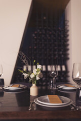 luxury tableware beautiful table setting in restaurant. banquette luxury arrangement plates and glasses. Glasses, forks, knives, napkins and decorative flower on a dark old brown wooden table.