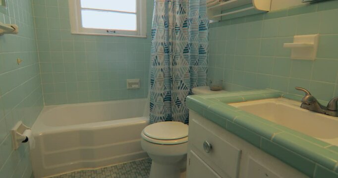 Slider shot of retro 1950s bathroom with original green tile walls and countertop.