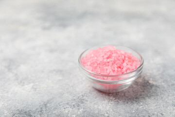 Sea salt for bath with aroma and rose flowers on textured wooden background. Pink sea salt. Spa treatments. Natural salt with herbs and essential oils. skincare concept. Meso for text. Copy space