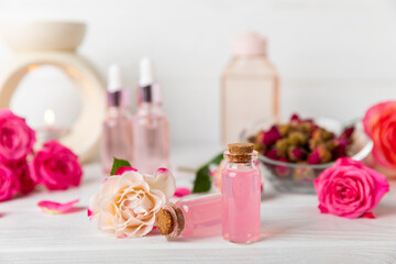 Rose essential oil on a textured background.Roses and a bottle of rose perfumed water.Aromatherapy treatment. Beauty concept. Spa procedure.Natural organic oil.Anti-stress,detox relax.Place for text