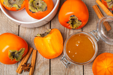 Persimmon jam with slices of ripe persimmon on wooden textured table. Delicious persimmon jam. Marmalade. Healthy sweets. Vegan. Close-up. Space for text. Copy space.