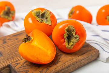 Persimmon on textured wooden background. Persimmon fruit. A piece of ripe, juicy, sweet persimmon fruit. Vegan. Orchard. Close-up. Space for text. Copy space.