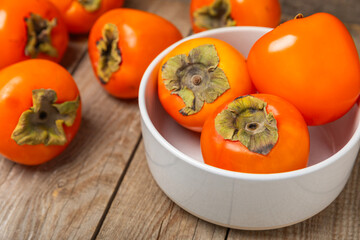 Persimmon on textured wooden background. Persimmon fruit. A piece of ripe, juicy, sweet persimmon fruit. Vegan. Orchard. Close-up. Space for text. Copy space.