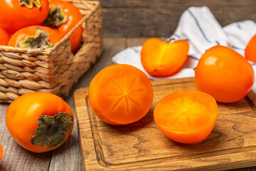 Persimmon on textured wooden background. Persimmon fruit. A piece of ripe, juicy, sweet persimmon fruit. Vegan. Orchard. Close-up. Space for text. Copy space.