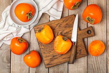 Persimmon on textured wooden background. Persimmon fruit. A piece of ripe, juicy, sweet persimmon fruit. Vegan. Orchard. Close-up. Space for text. Copy space.
