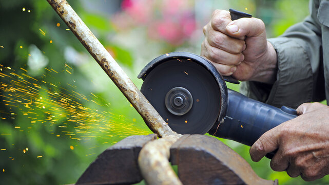 Heavy industry worker cutting steel with angle grinder. Cutting an old rusty pipe. dismantling. close-up. old pipe and work with grinder. hands of a master, professional. sparks of hot metal fly - Powered by Adobe