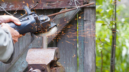 Heavy industry worker cutting steel with angle grinder. Cutting an old rusty pipe. dismantling. close-up. old pipe and work with grinder. hands of a master, professional. sparks of hot metal fly