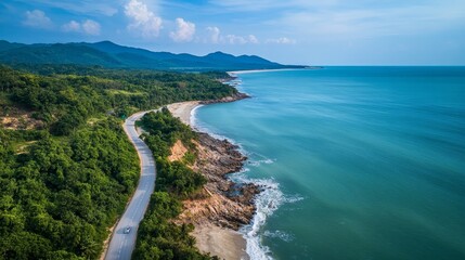 Fototapeta premium Scenic Coastal Road Winding Through Lush Green Hills Along the Serene Blue Waters of the Ocean in a Tropical Paradise